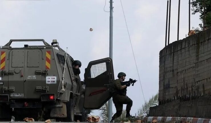Tentara Israel membidik senjata dari samping kendaraan lapis baja di tepi jalan