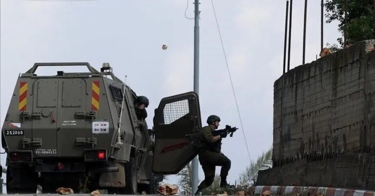 Tentara Israel membidik senjata dari samping kendaraan lapis baja di tepi jalan