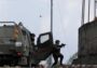 Tentara Israel membidik senjata dari samping kendaraan lapis baja di tepi jalan
