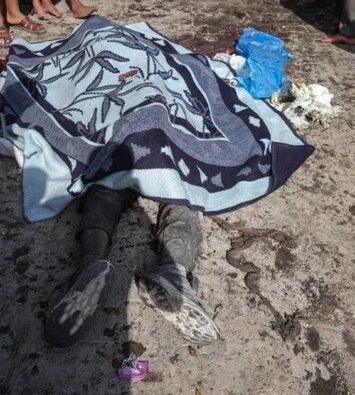 Jenazah warga Palestina ditutup selimut di jalan, dikelilingi warga di Gaza.